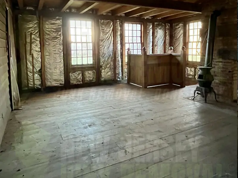 An attic loft cleared down to a swept wood floor, with daylight coming through the windows
