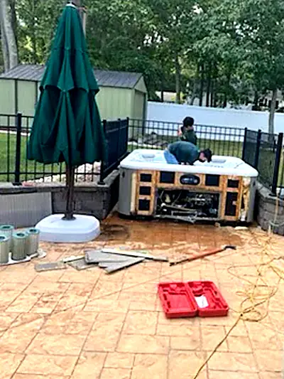 An old hot tub on a patio with its side panels removed