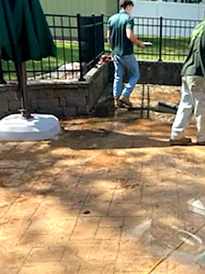 The crew cleaning the patio after the hot tub was removed
