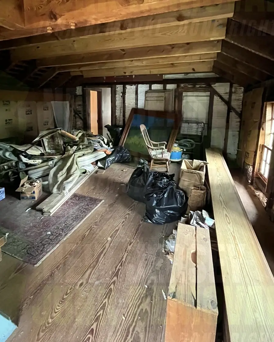 Before: an attic loft with lumber, bags and old furniture on the floor