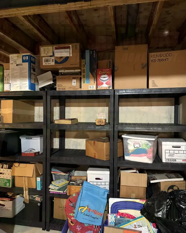 Before: black basement shelving units full of boxes, bins and electronics cartons