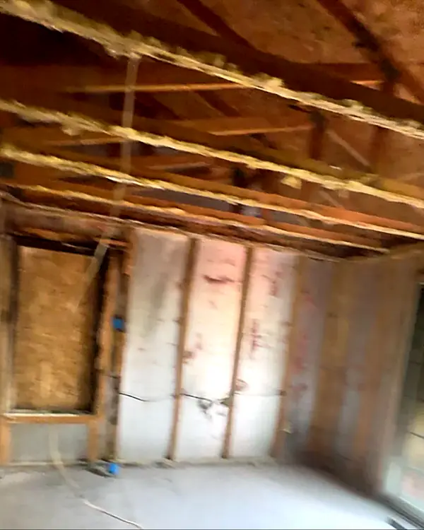 After: the same room gutted down to bare studs and ceiling joists