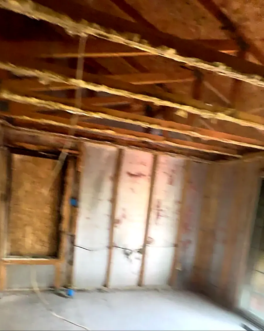 After: the same room gutted down to bare studs and ceiling joists