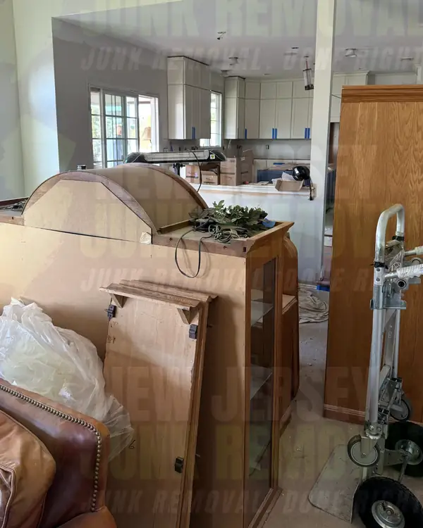 Before: a room under renovation with a wood glass-front cabinet, a tall wood cabinet piece and a hand truck