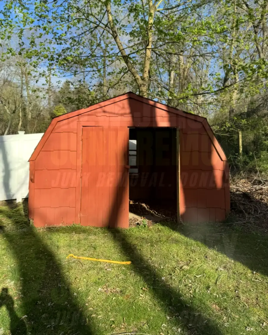 Before: a weathered red wooden shed in a backyard
