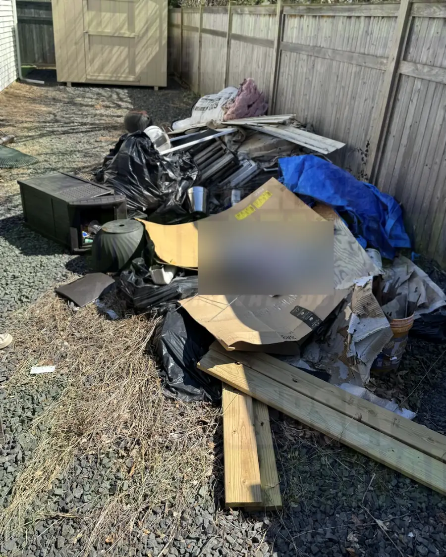 Before: renovation debris, lumber and bags piled along a side yard fence