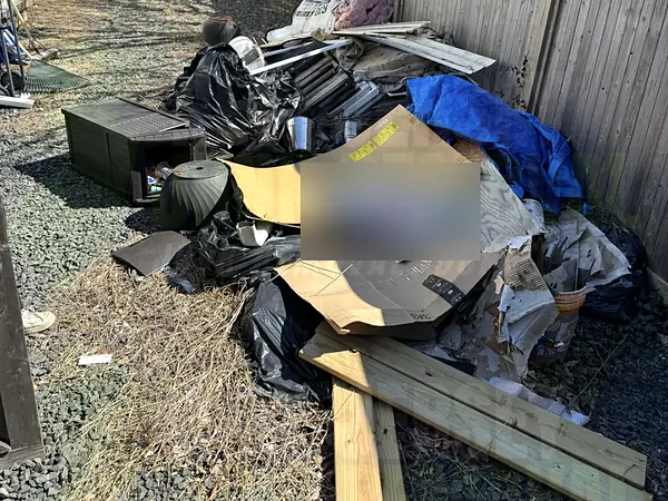 Renovation debris and lumber piled along a side yard