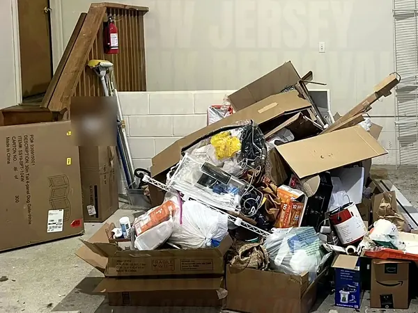 A garage corner piled with boxes and household junk before a cleanout