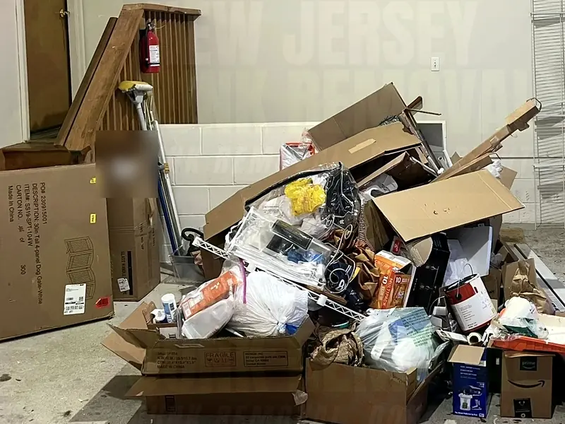 A garage corner piled with boxes and household junk before a cleanout