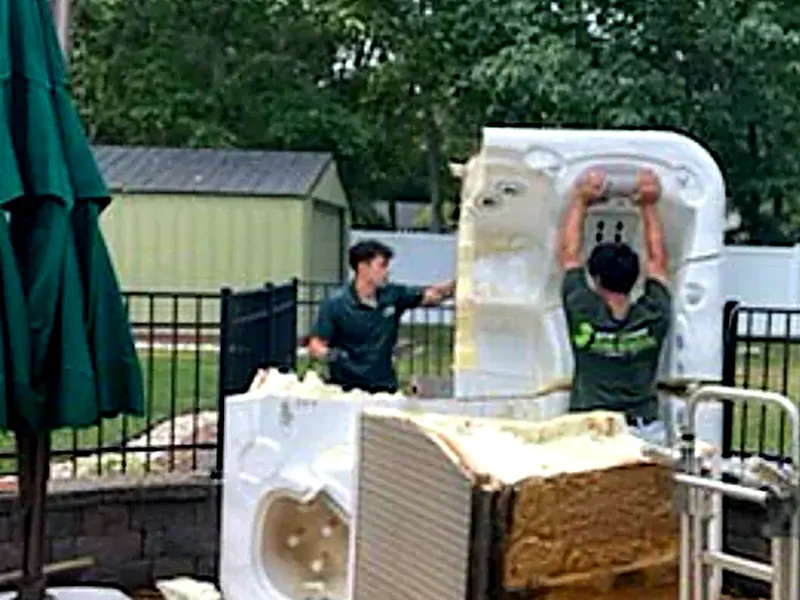 The crew cutting apart an old hot tub on a backyard patio
